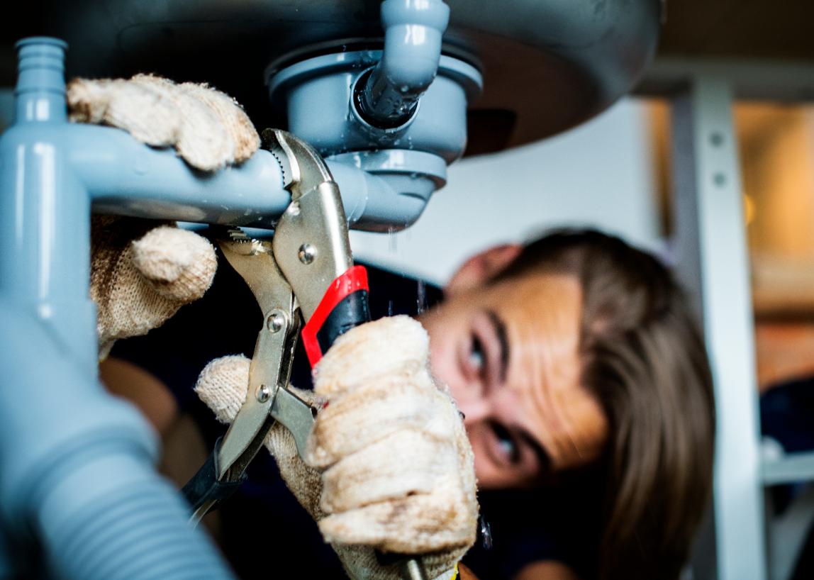 Plumber fixing kitchen sink with professional tools