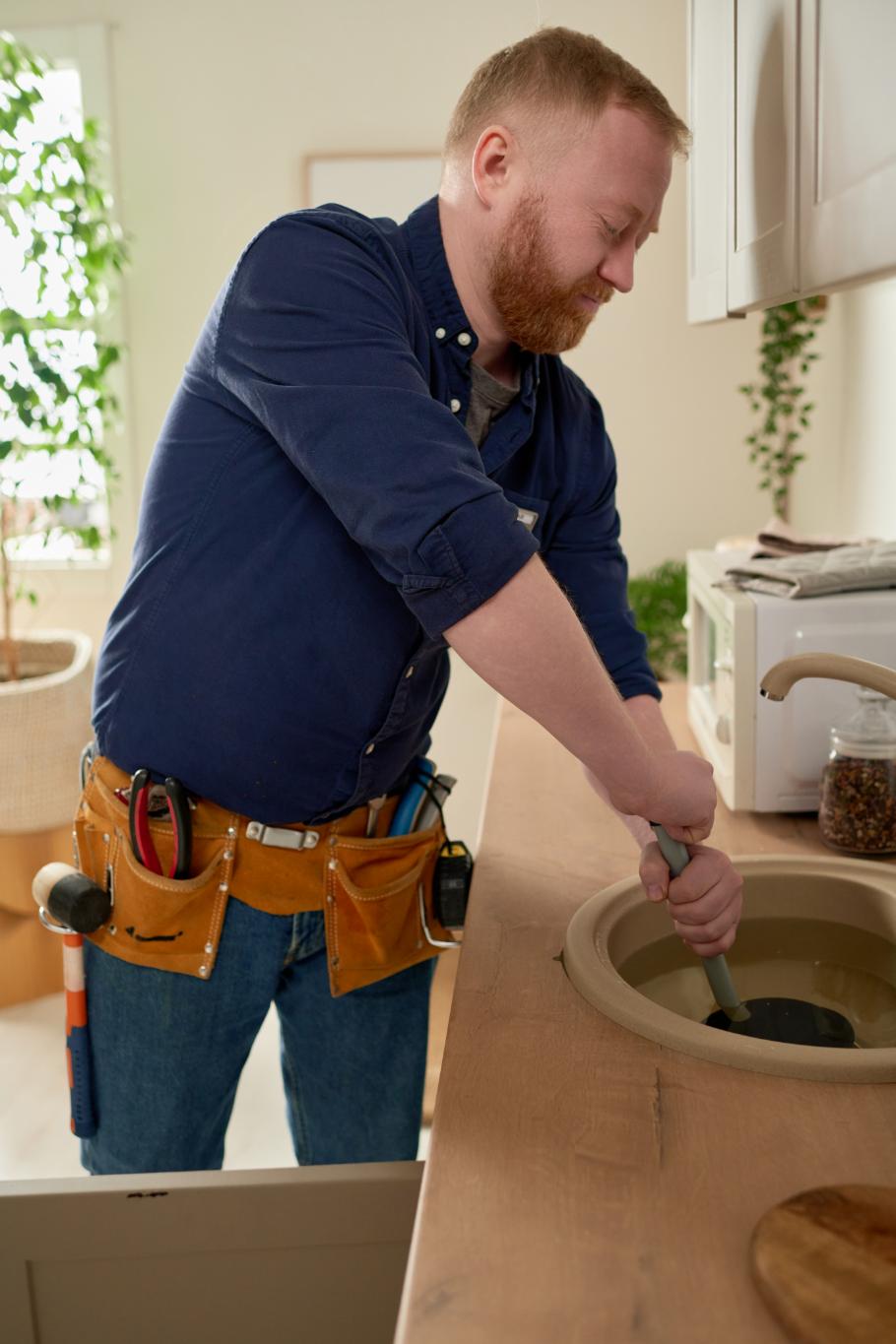 Plumber loosening slip nut under sink